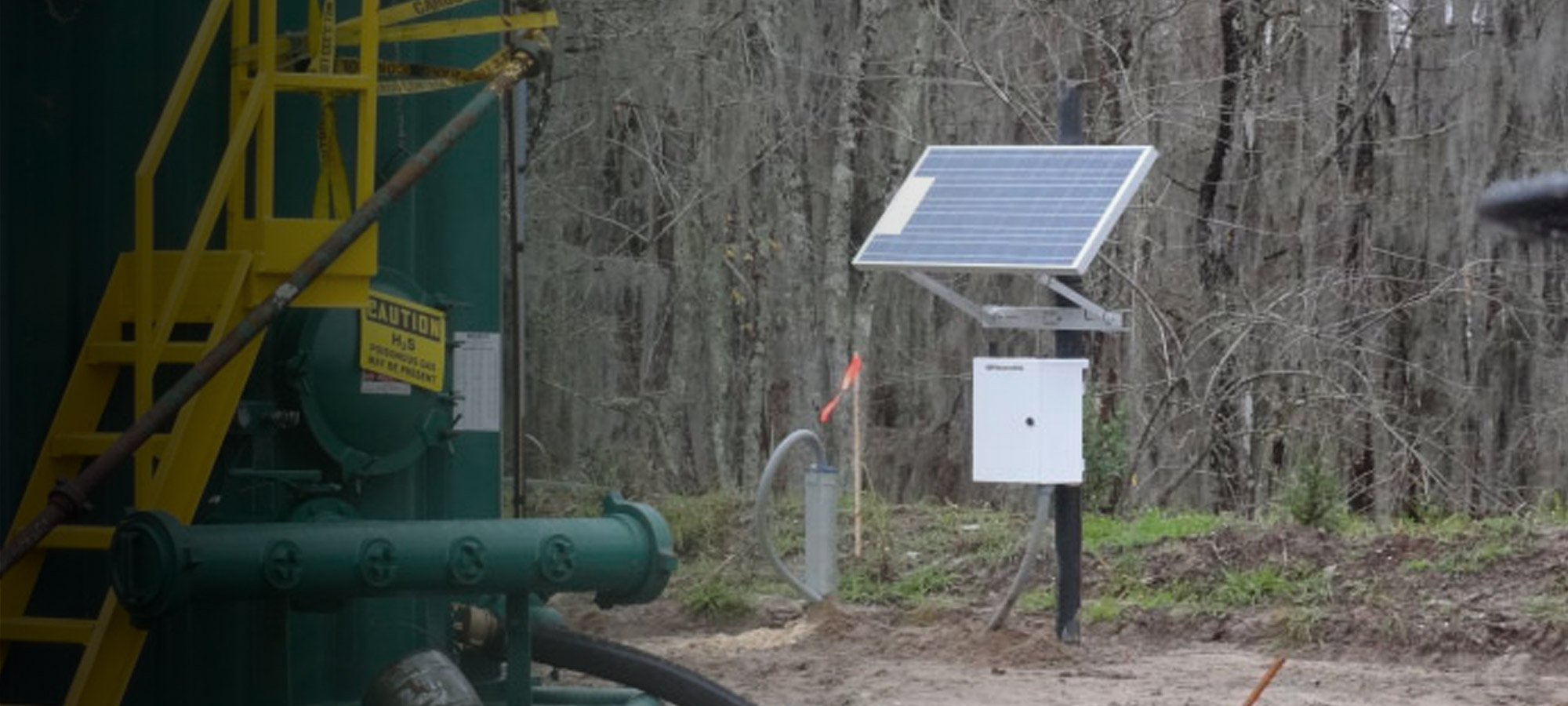 Monitoring station with solar panel attached to a post in a wooded area