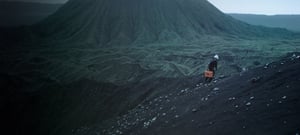Scientist walking up the side of a mountain with a pelican case in hand