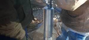 Two technicians Trillium 120 Borehole being lowered into a pipe.