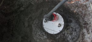 Trillium compact seismometer sitting in a posthole in the earth connected to a large cable