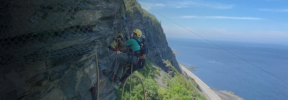 Scientists suspended cliffside on ropes installing equipment