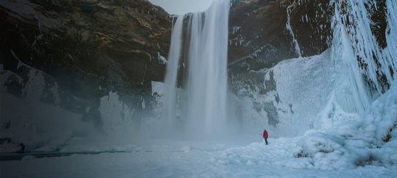 Scientist standing at the bottom of a frozen waterfall