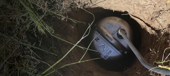 Trillium Horizon Seismometer attached by a cable buried in a hole in the ground.