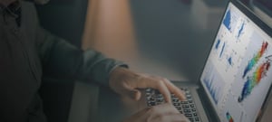 Hands working on a laptop keyboard with seismic data on the screen