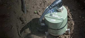 Green Trillium Compact sitting in a dug hole in the earth with large cable attached