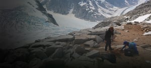 Scientists burying a Nanometrics Seismometer on the side of an ice cliff.