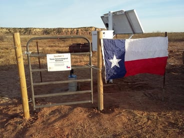 A textnet seismic station behind a fence with a Texas flag on it.