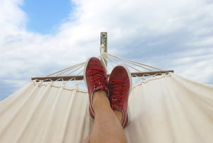 First person view of a man's legs relaxing on a hammock