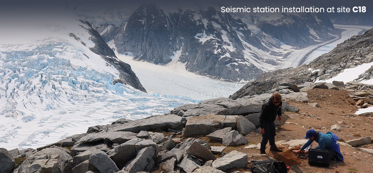 Scientist burying a seismometer in the ground with mountain backdrop